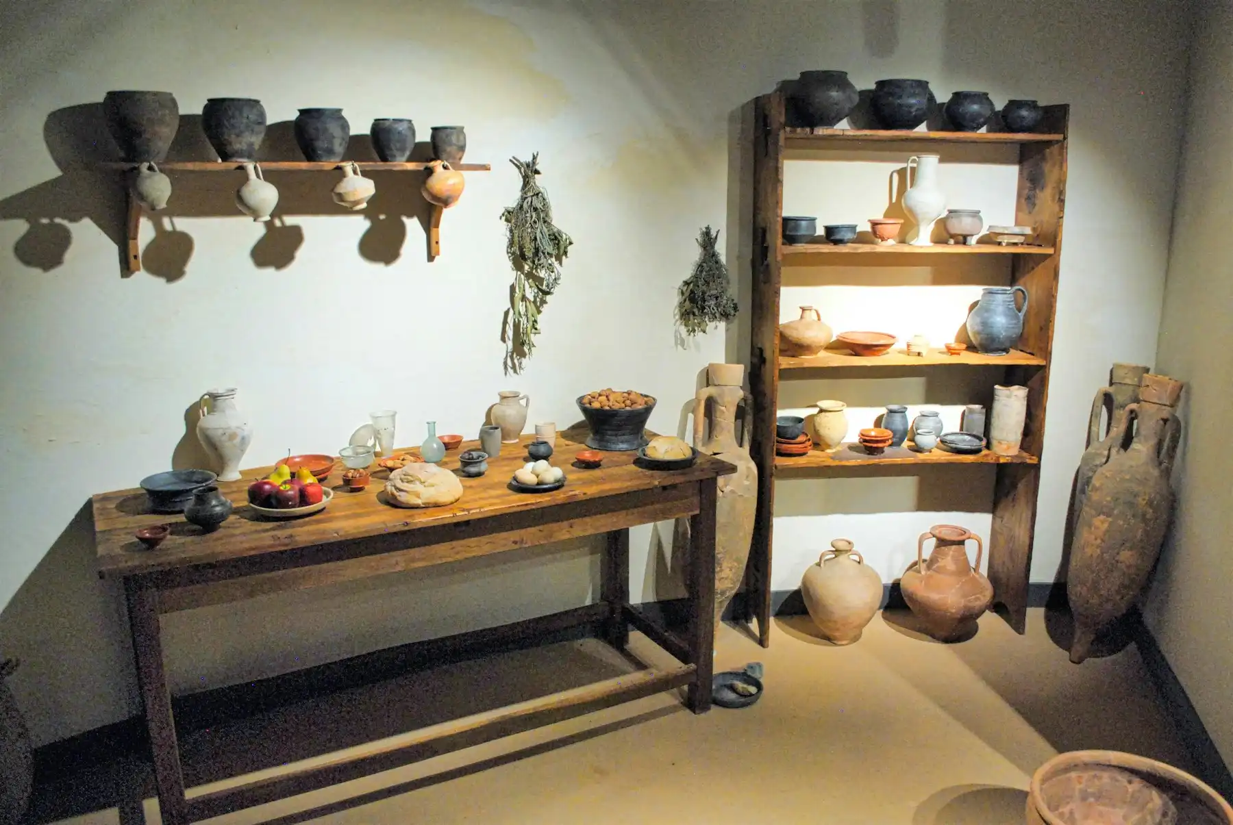 A gallery room of antique clay jars, amphorae and pottery under warm spotlights