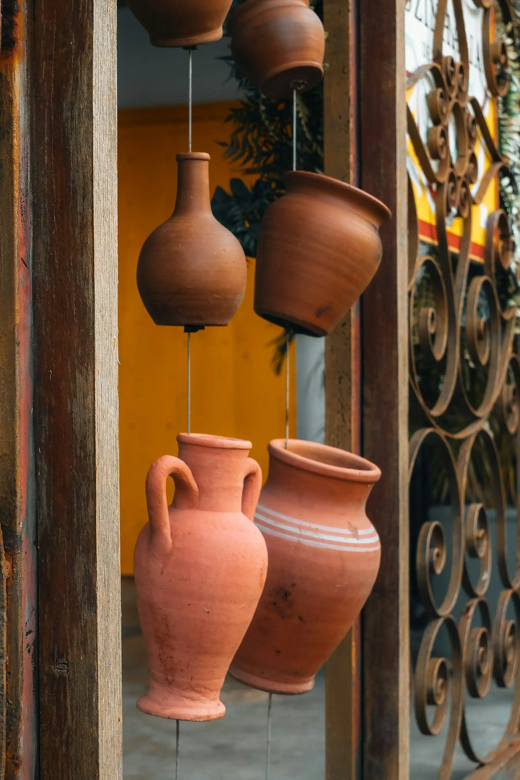 Terracotta wine jugs and amphorae hanging in a weathered wooden doorway