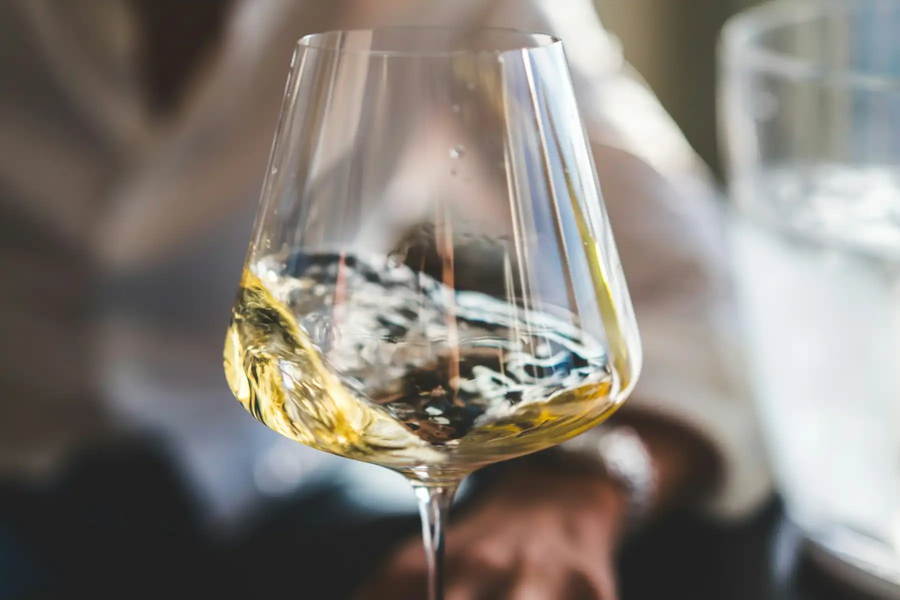 Pale gold white wine swirling in a tasting glass