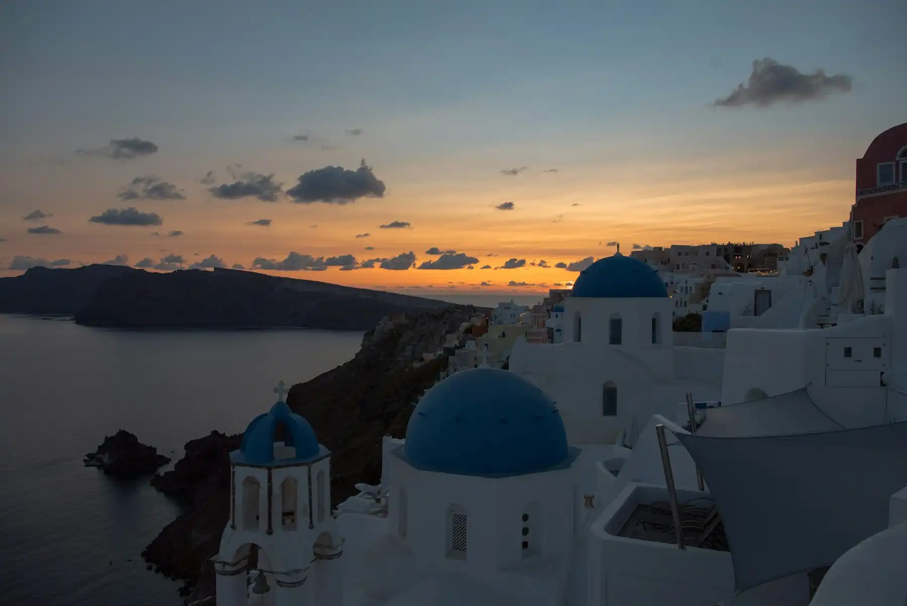 Blue domes and whitewashed terraces of Oia in the quiet light just after sunset
