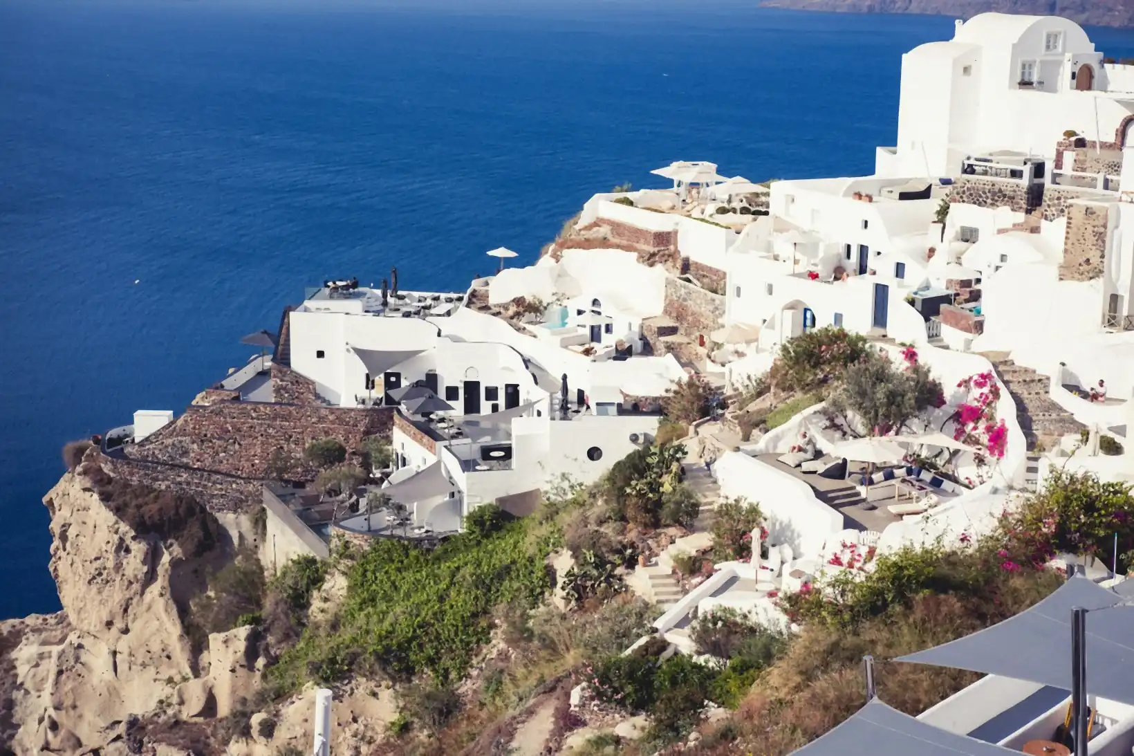 Whitewashed cave houses and volcanic-stone terraces stacked above the deep blue Aegean on the Oia cliffside