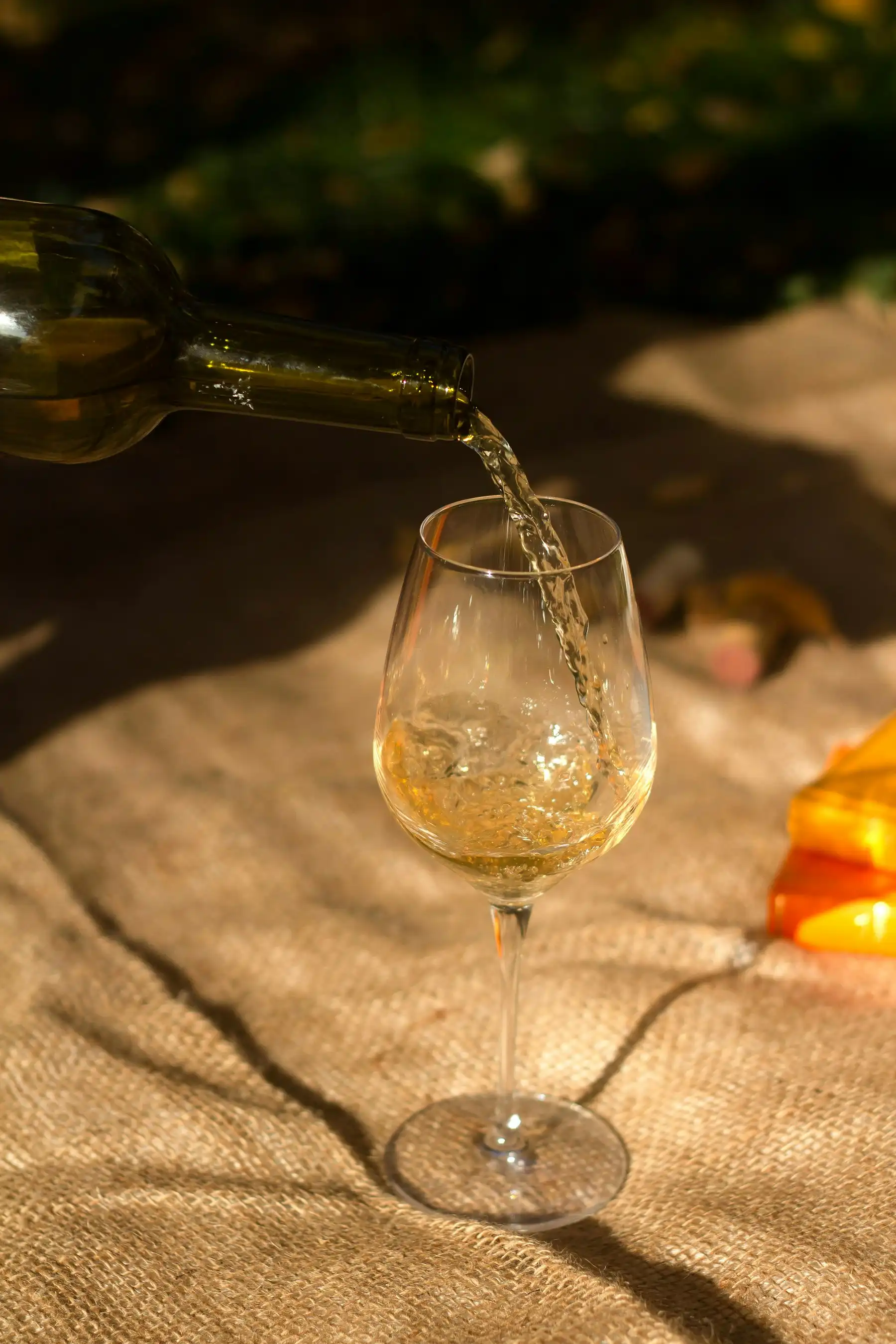 Amber sun-dried-grape wine pouring into a glass in low golden light